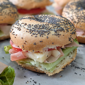 Bagel sandwich with ham, cheese, and lettuce on a marble surface